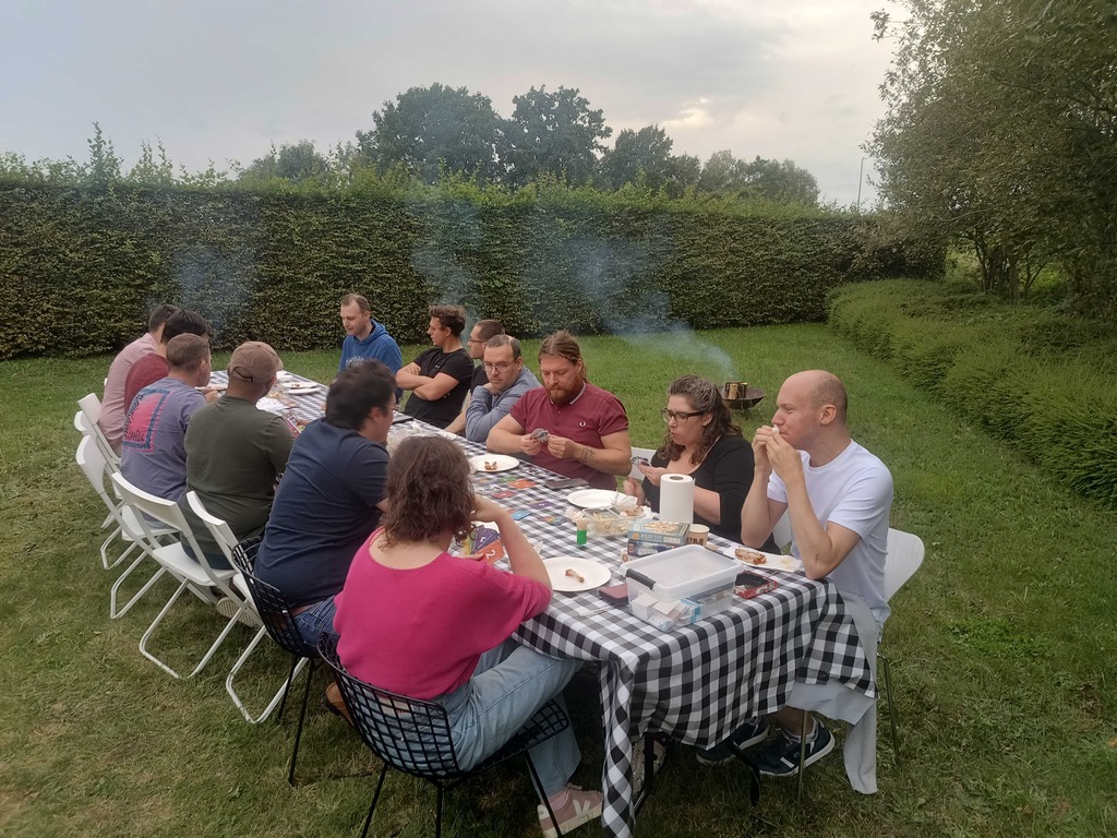 The team shares a meal, enjoying food and conversations in a relaxed IT setting.