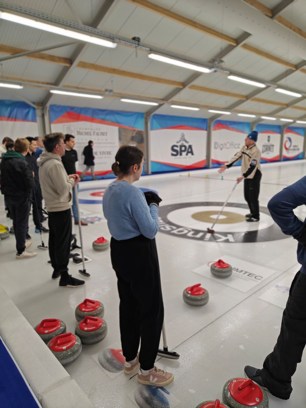 A dynamic indoor curling session with players and a coach emphasizes teamwork, precision, and the growing appeal of the sport in a modern, well-equipped facility.