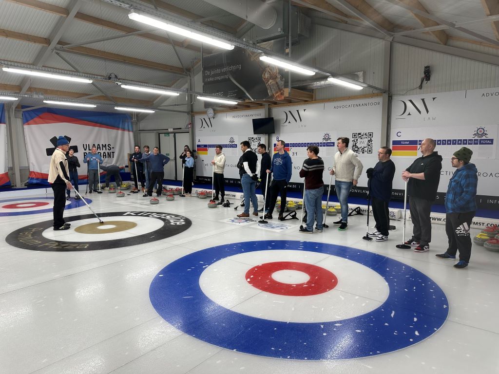 A group curling session in a professional indoor arena highlights coaching, teamwork, and precision, showcasing the sports community and engaging atmosphere.