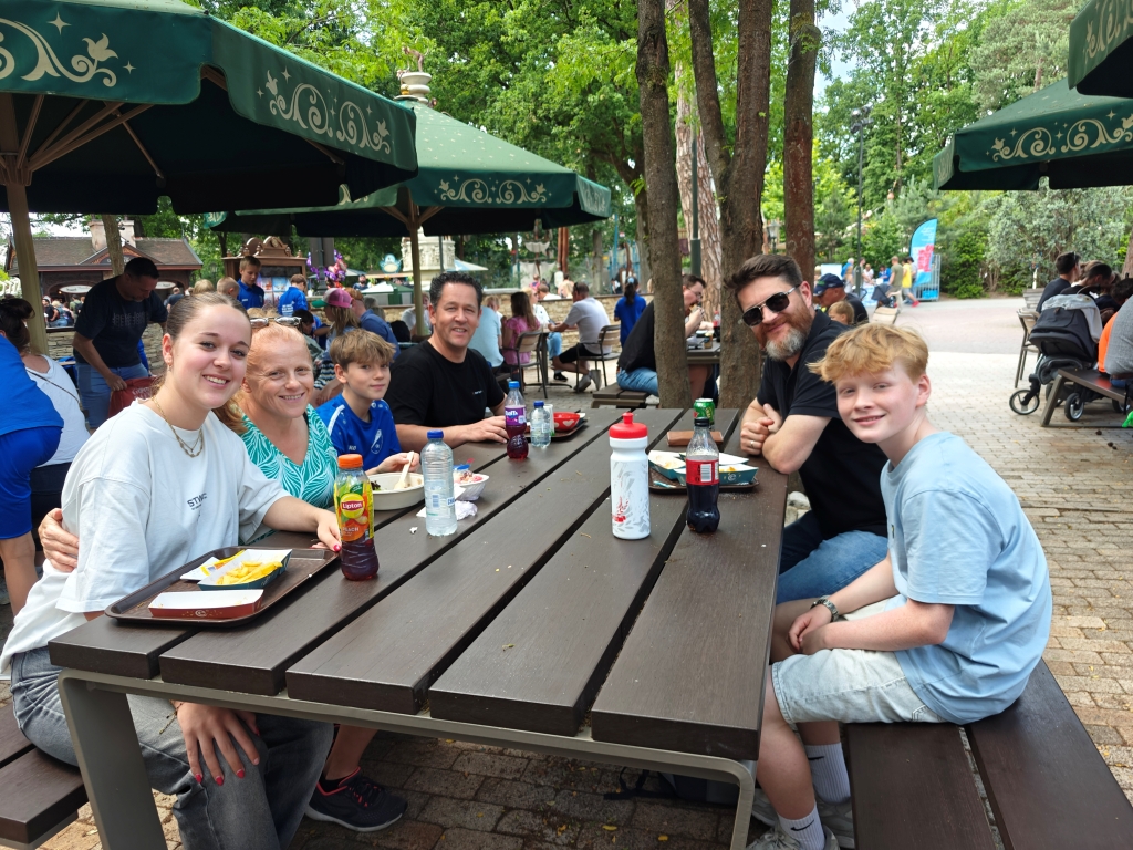 Families of Itenium employees smiling and enjoying a shared meal at Efteling's Family Day, capturing the essence of team appreciation and a fun-filled company event.