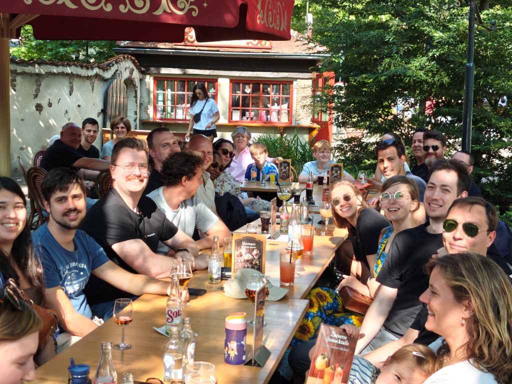 A lively gathering of Itenium employees and their families at Efteling, enjoying drinks and conversation, highlighting a fantastic corporate family outing filled with laughter and camaraderie.