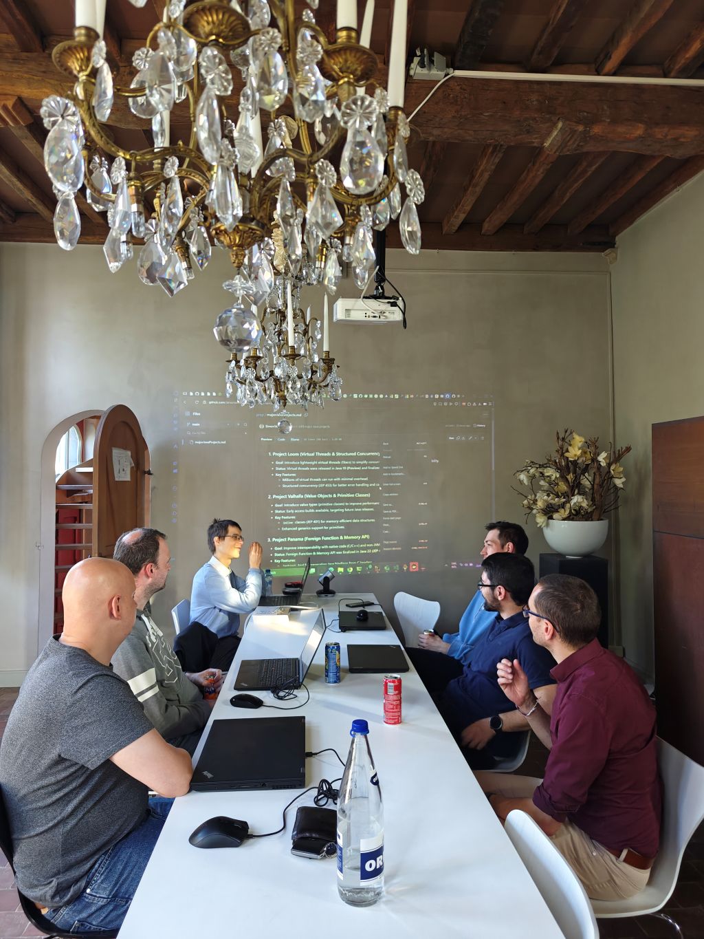 A collaborative group of software developers actively participating in a workshop, exploring the latest Java 17-24 features. Laptops open and engaged discussion highlight a dynamic tech training session.