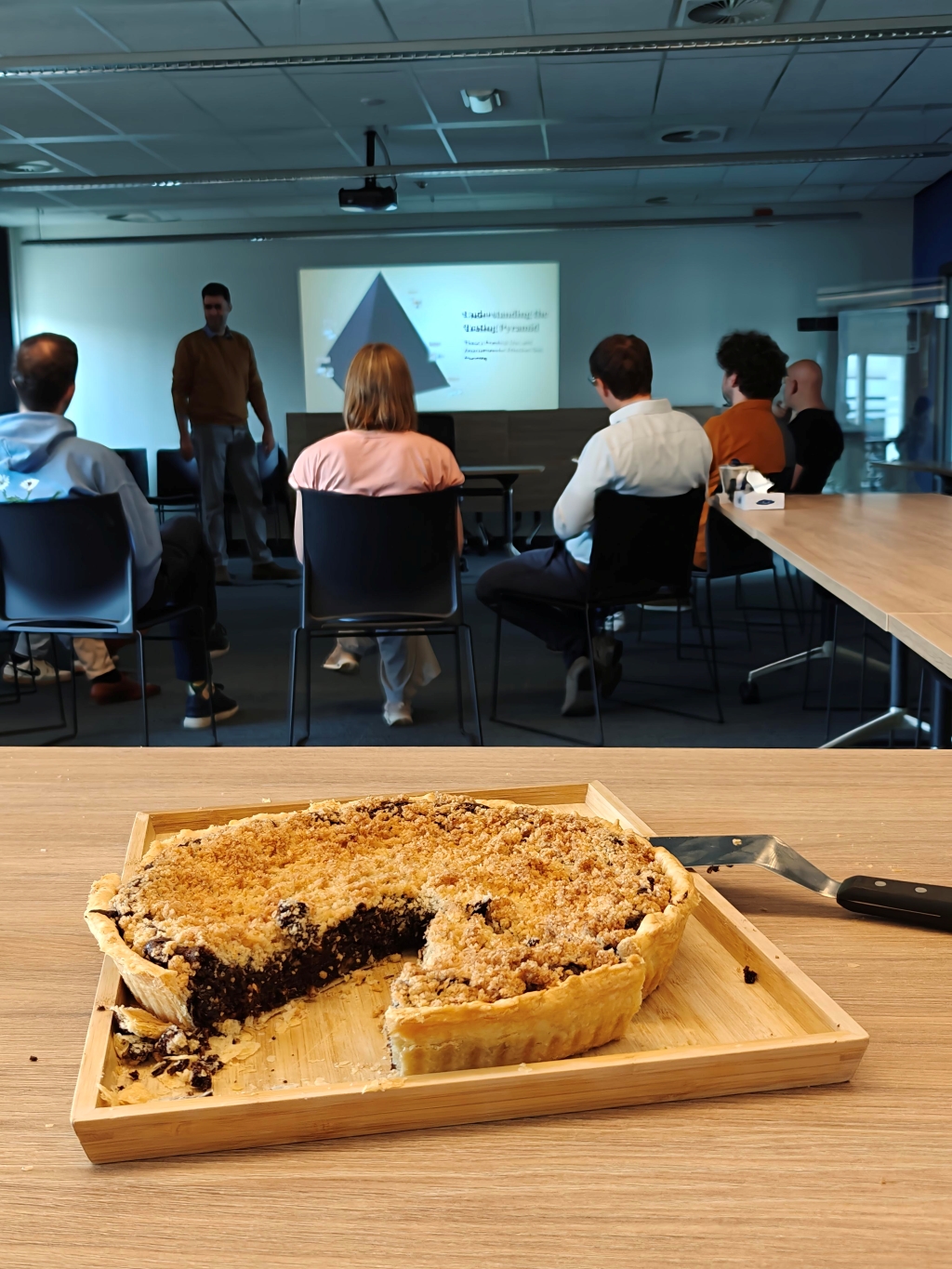Developers attentively listen to a presenter explaining the Testing Pyramid during a valuable learning lunch session at an Office Day. This highlights a key moment of software testing education and knowledge sharing.