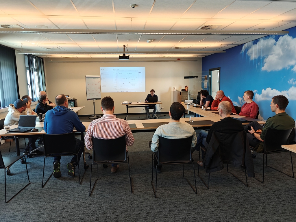 A large group of developers and consultants attending a presentation during the Itenium Open Space Day, actively participating in a collective learning session and exploring diverse tech topics. This showcases a collaborative learning environment.