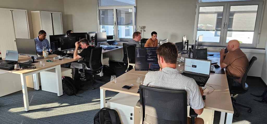 Itenium Java and .NET consultants collaboratively engaged in a hands-on unit testing session, focusing on Test Driven Development and TestContainers for robust software solutions in a modern office environment.