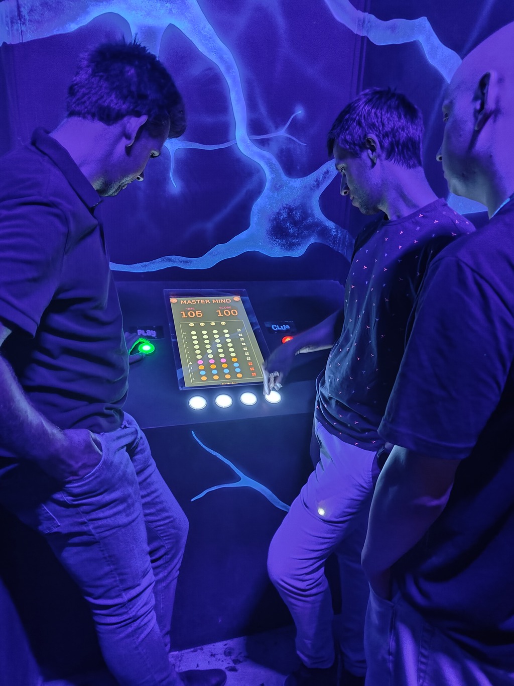 The team engages with buttons in a puzzle-solving task, as the screen displays a Mastermind game, showing the remaining time and current score.